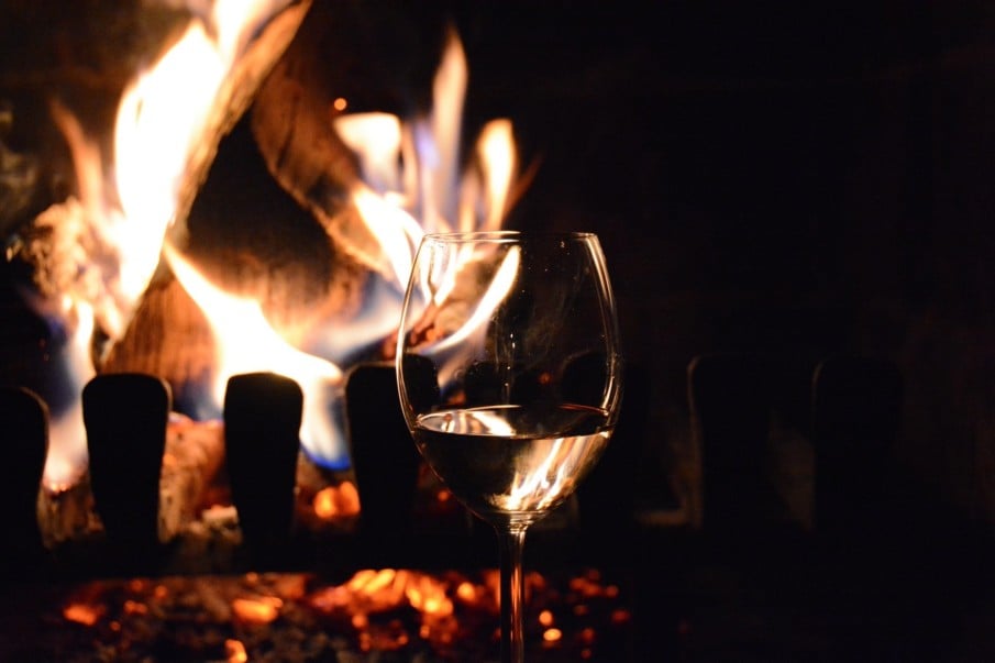winter wines - glass with fire Glass of wine in front of roaring fireplace