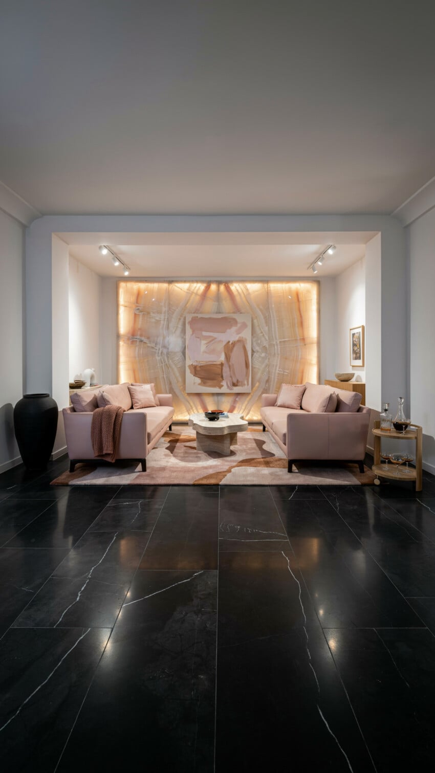 Backlit Onyx Accent Wall with Blush Sofas and Black Marble Floor