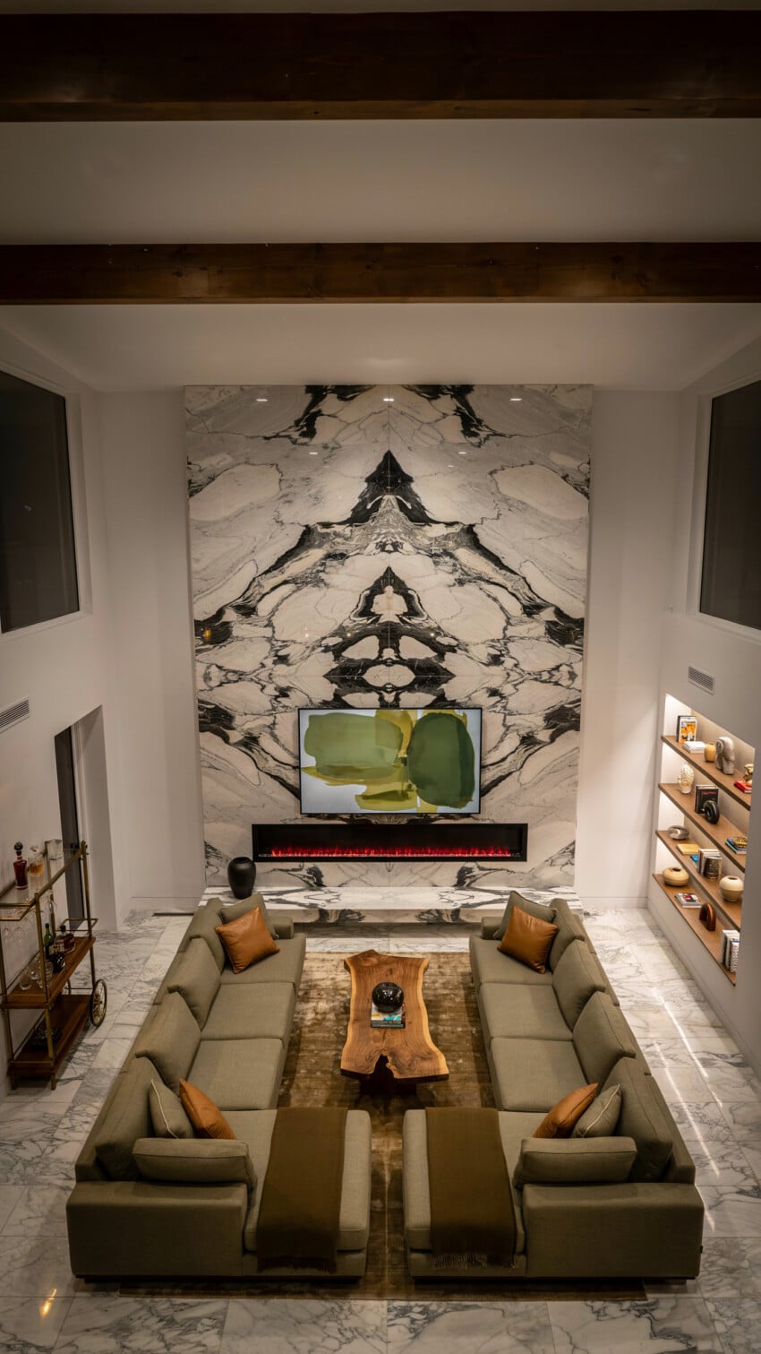 Bookmatched Marble Accent Wall with Sage Sectional and Exposed Beam Ceiling